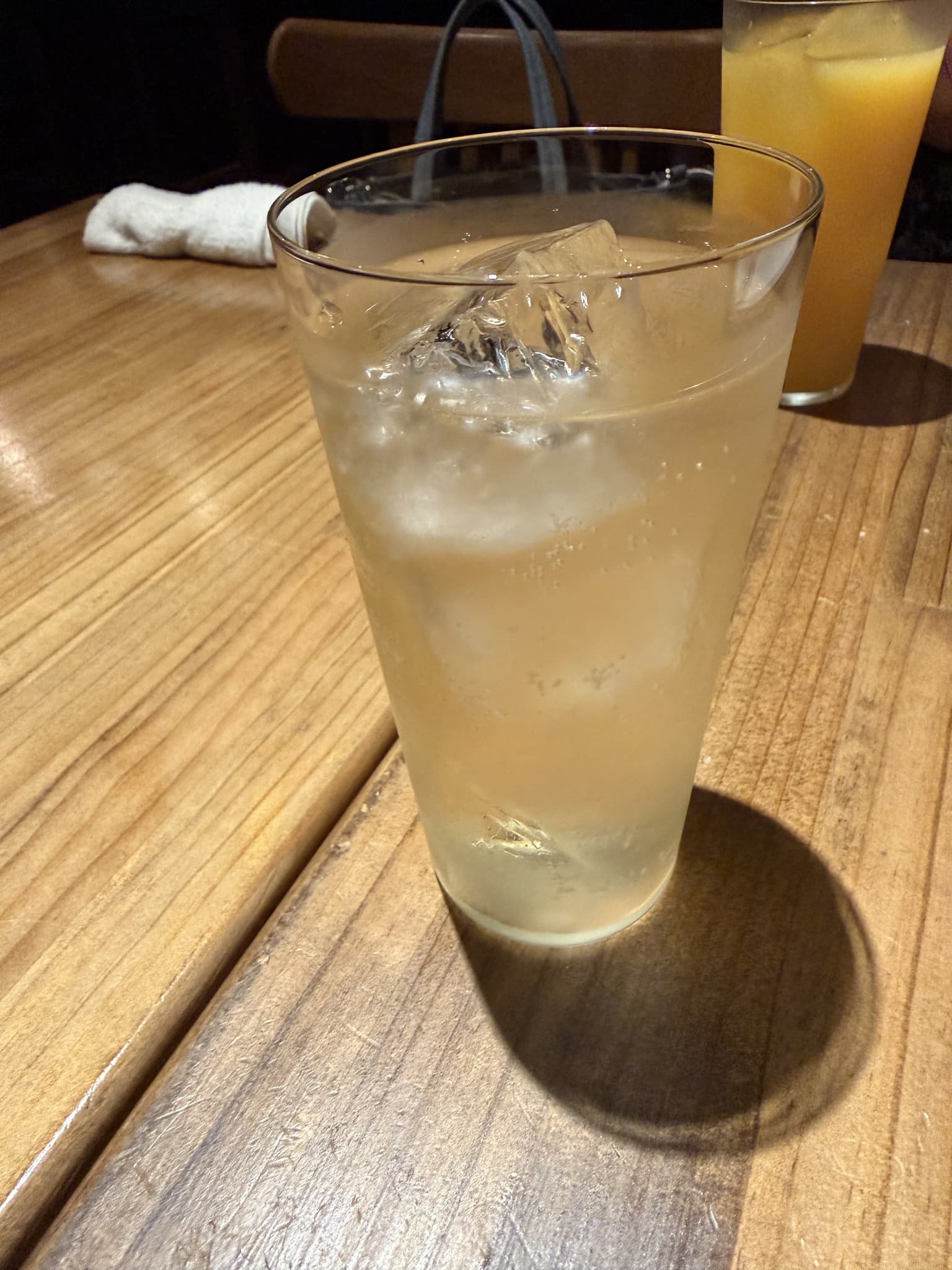 木のテーブルに置かれた、氷の入った背の高いグラス