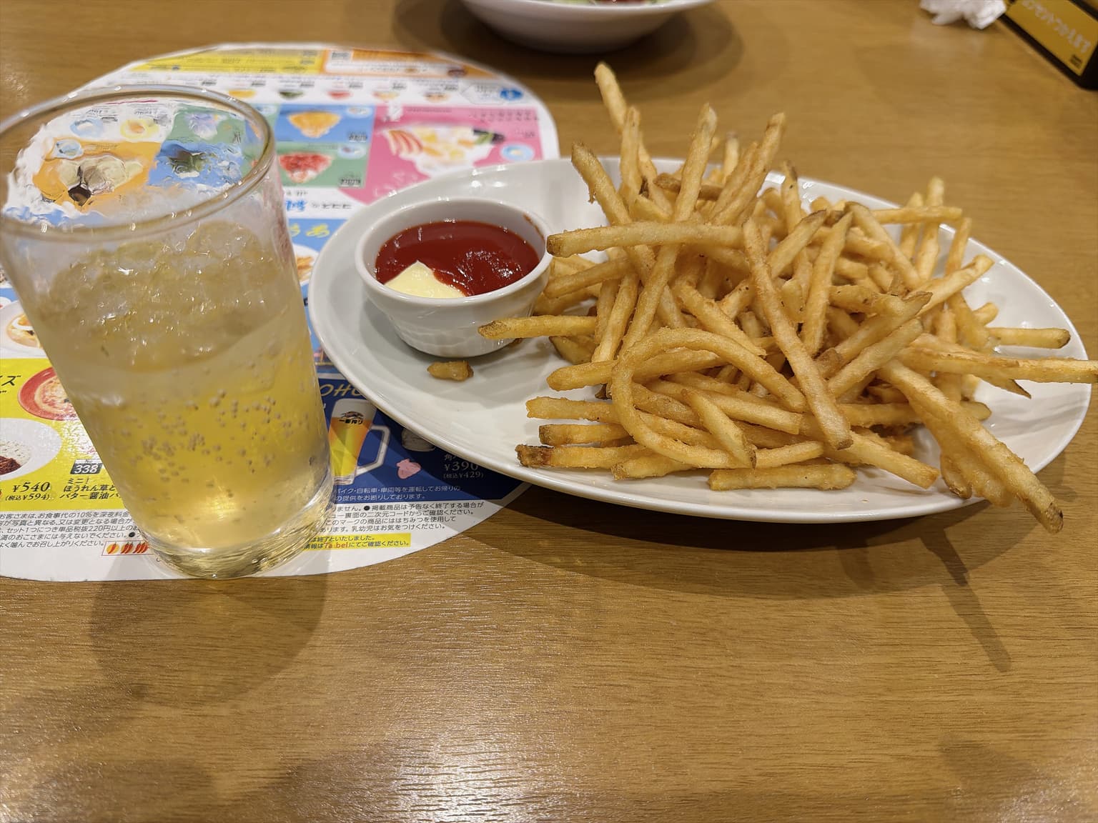 揚げ物と小皿のそばに置かれた、氷入りのハイボール