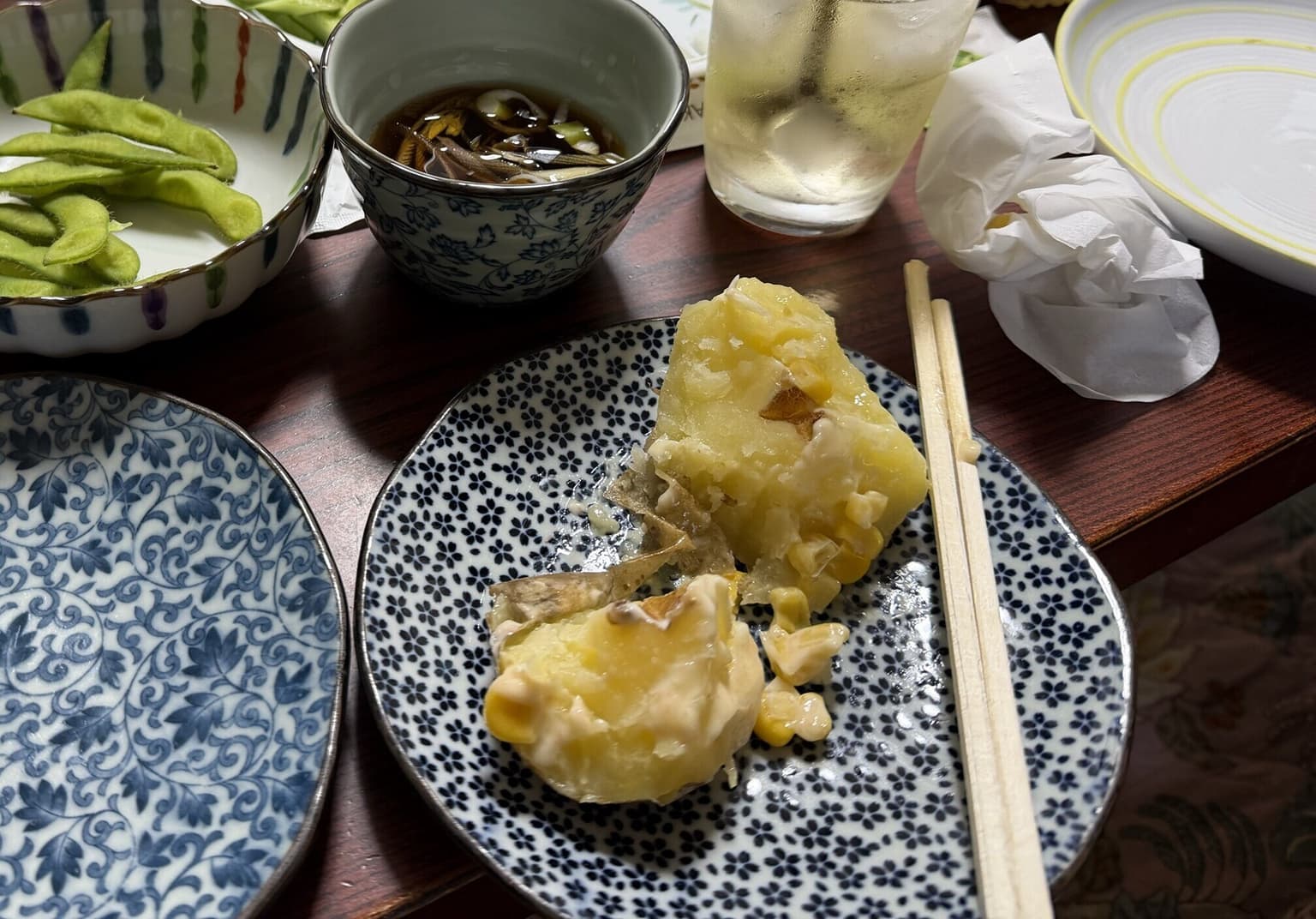 夕食の小皿料理とともに木の食卓へ置かれたハイボール