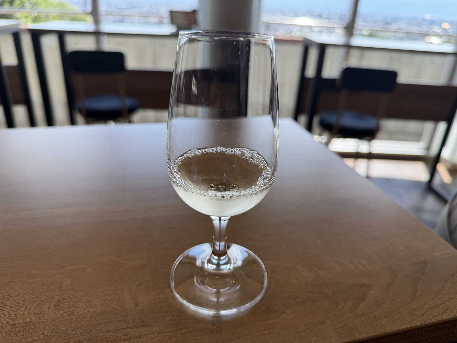 シャトー酒折の木のテーブルに置かれた、淡い色の液体が少量入った脚付きグラス